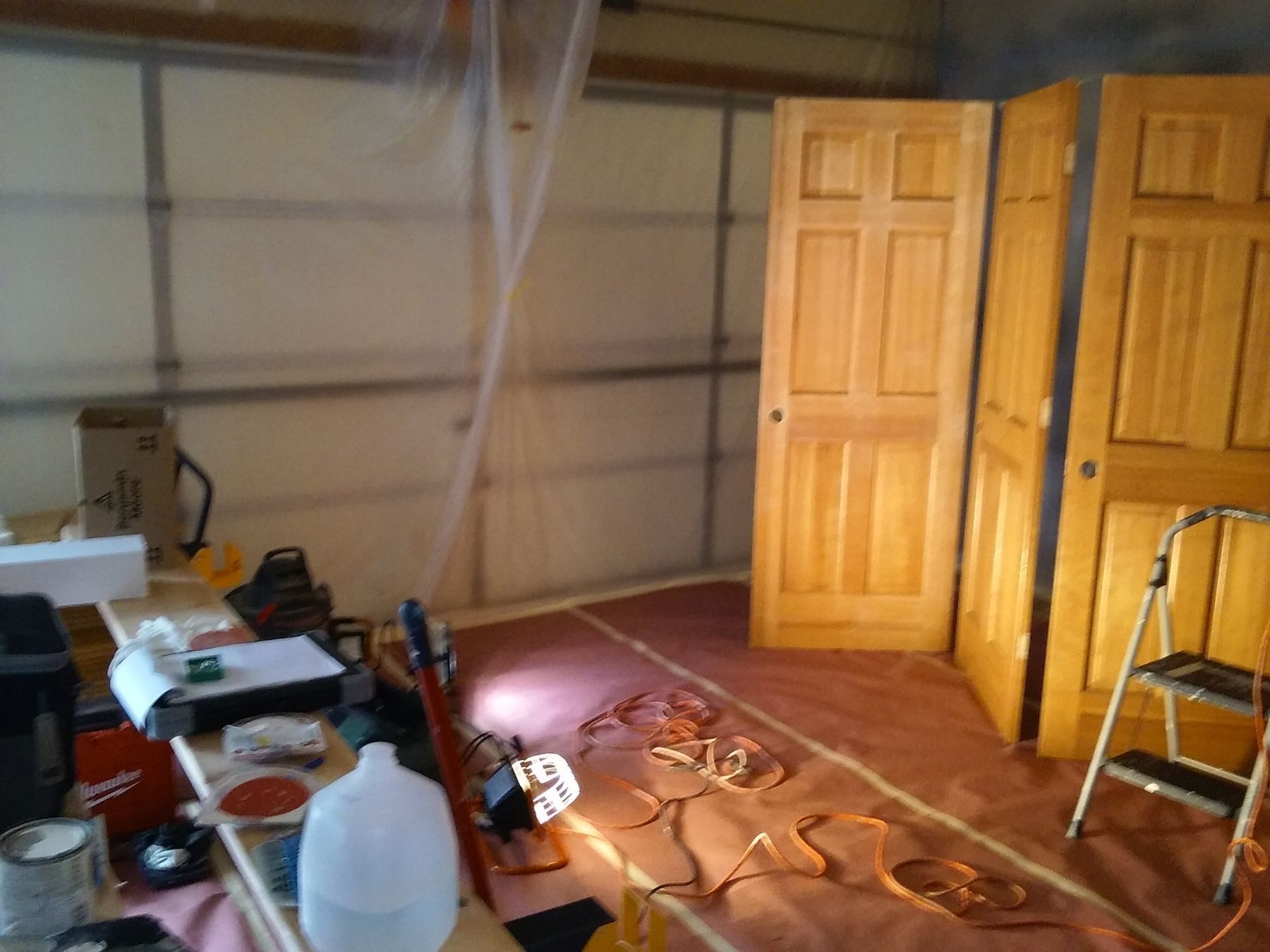 Oak interior doors set up in a plastic-lined spray booth