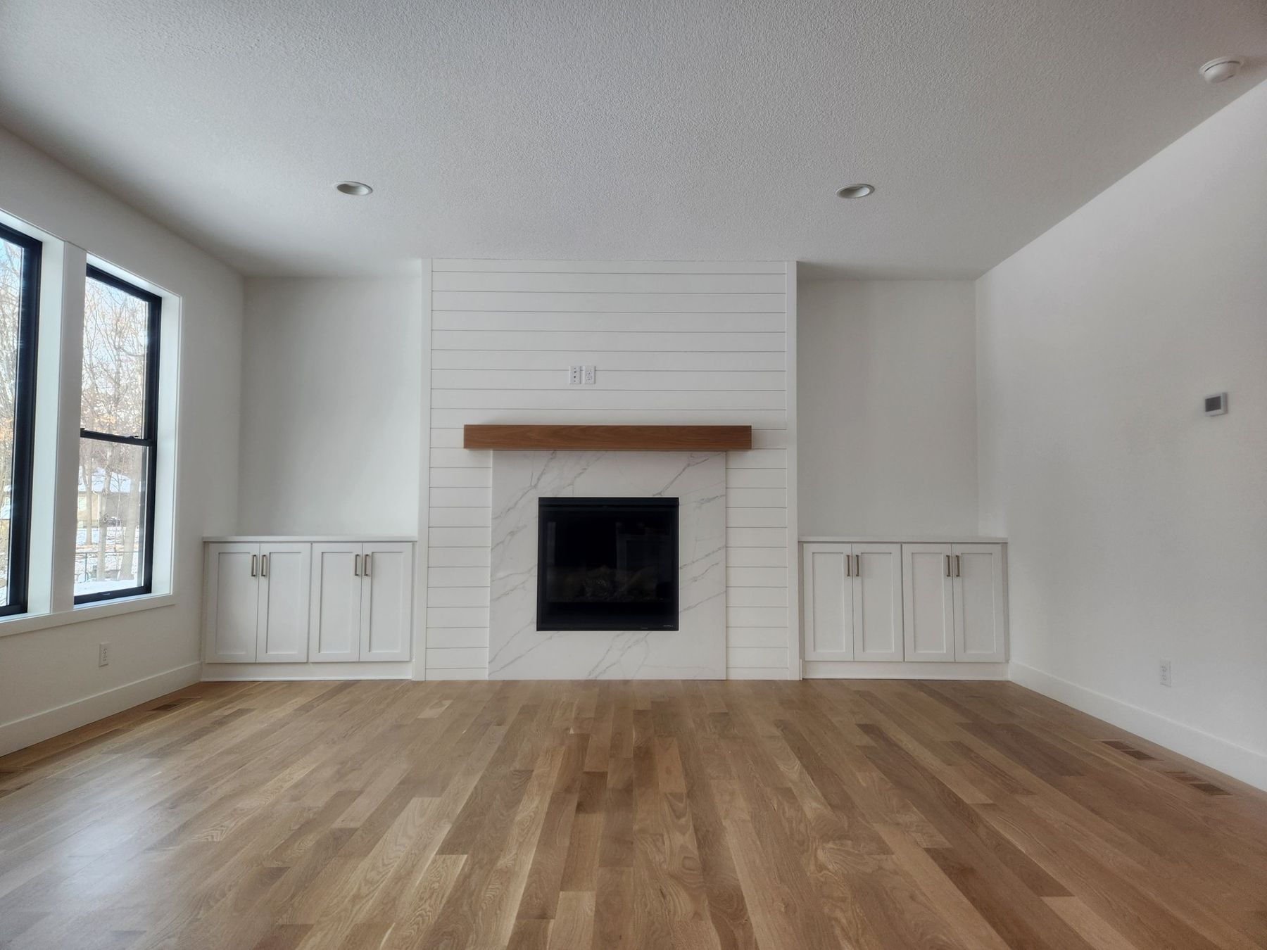 Living room with a white shiplap fireplace surround and built-ins