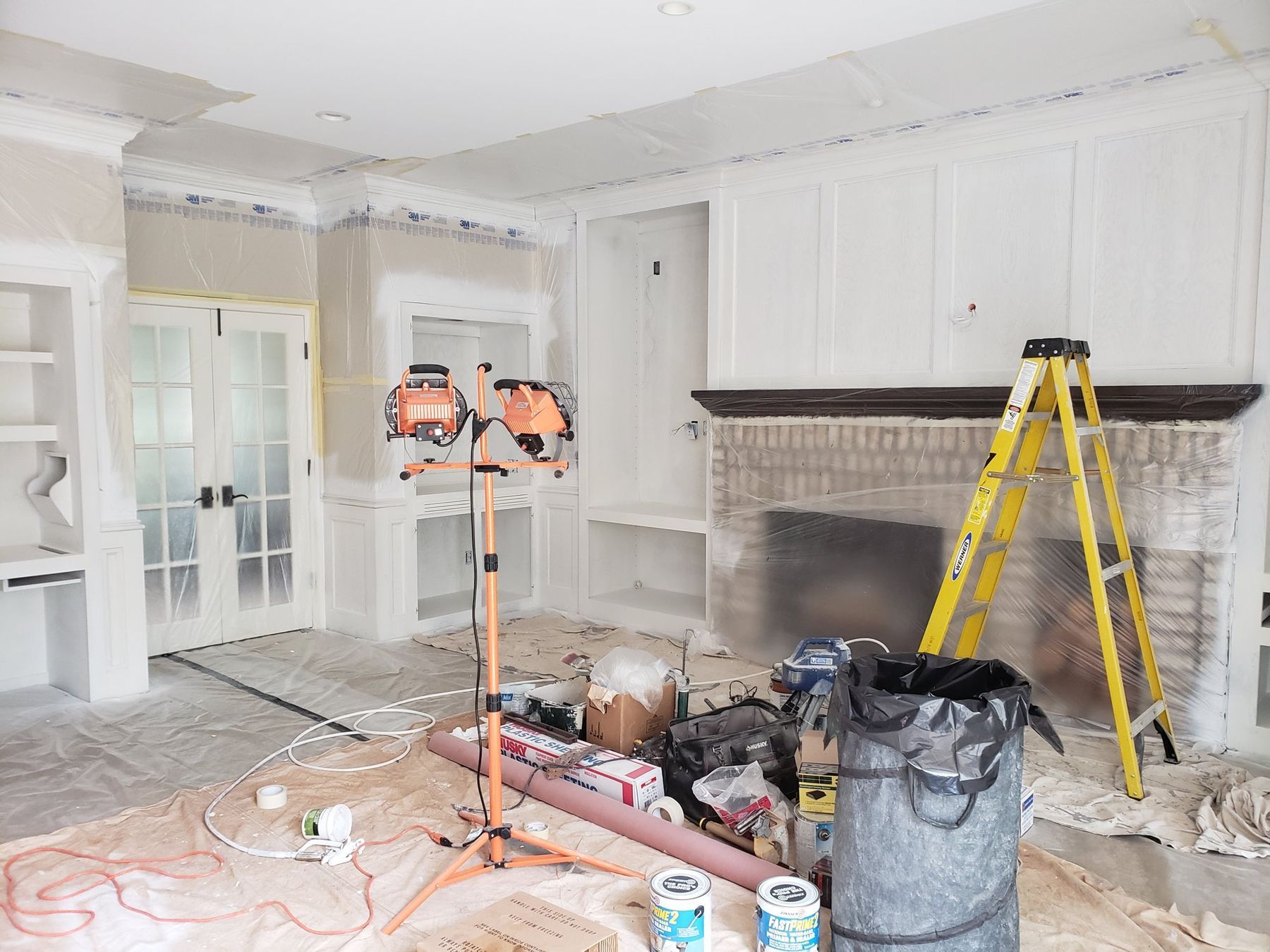 Family-room built-ins primed white, work lights set for inspection